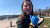 A person with long hair wearing a blue glove and smiling.​