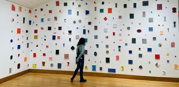 a person is viewing an installation of paintings