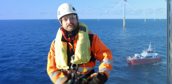 a man wearing an orange jacket standing in front of the sea