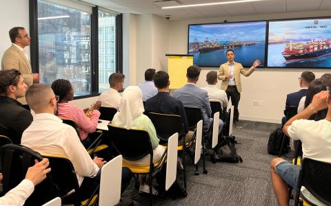 group of students in a class room with 2 big TV screens